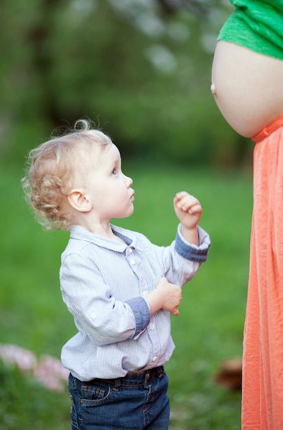 Ragazzino sveglio che esamina la pancia delle mamme incinte