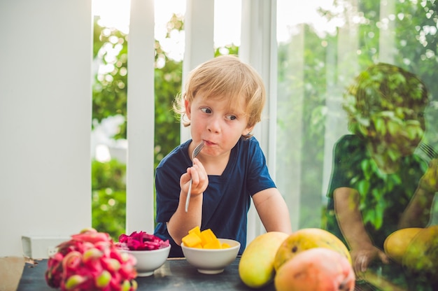 Ragazzino sveglio che mangia mango sulla terrazza.