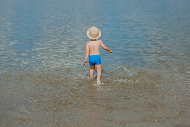 Ragazzino sveglio che passa l'acqua alla spiaggia