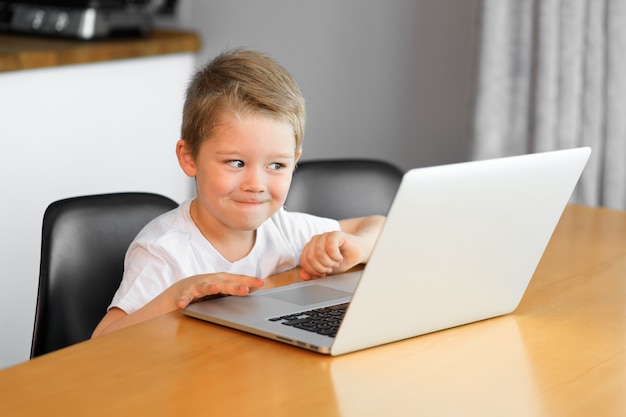 Ragazzino sveglio che per mezzo di un computer portatile