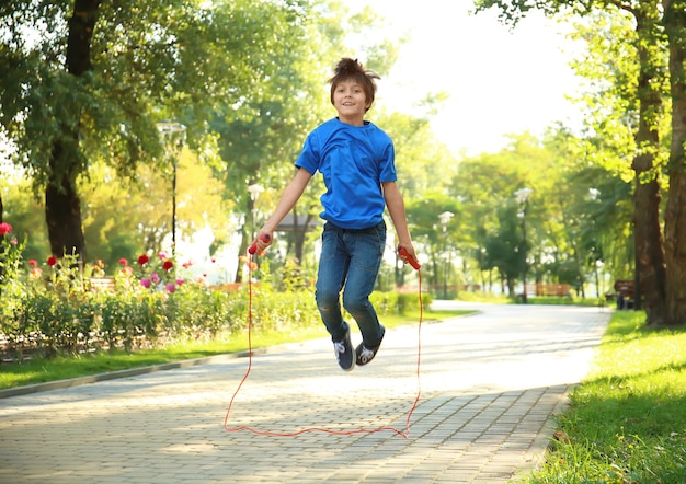 Ragazzino sveglio che salta la corda nel parco