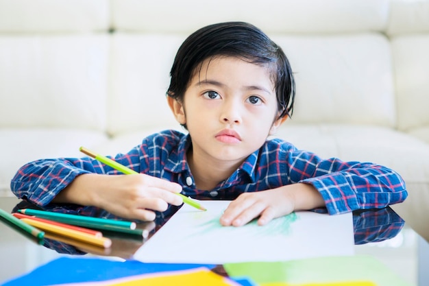 Ragazzino sveglio che studia da casa mentre disegna