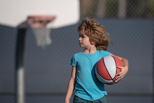 Ragazzino sveglio che tiene una palla da basket che prova a fare un punteggio