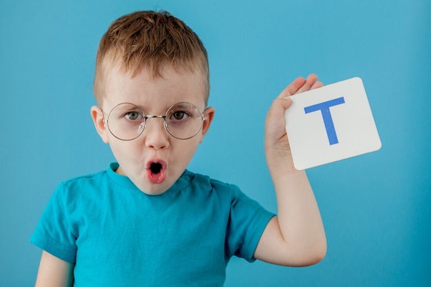 Ragazzino sveglio con la lettera Bambino che impara a lettere. Alfabeto