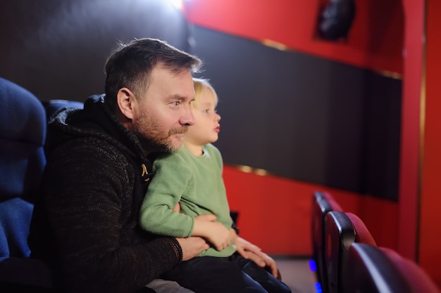 Ragazzino sveglio con suo padre che guarda film del fumetto nel cinema