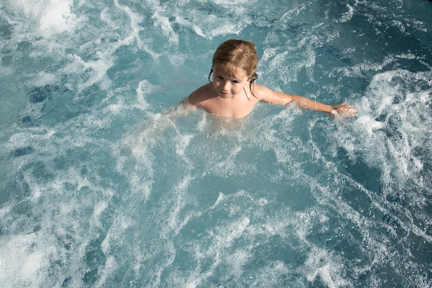 Ragazzino sveglio sorridente in piscina. Il bambino gioca in acqua durante le vacanze al mare.