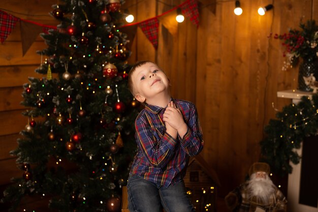 Ragazzino sveglio vicino all'albero di Natale