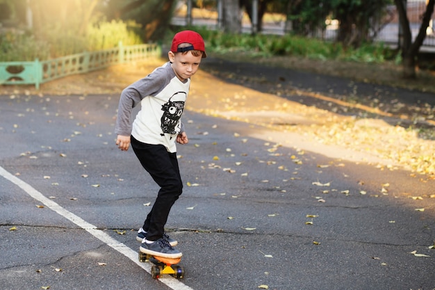 Ragazzino urbano con uno skateboard da penny. Ragazzino che guida nel parco su uno skateboard