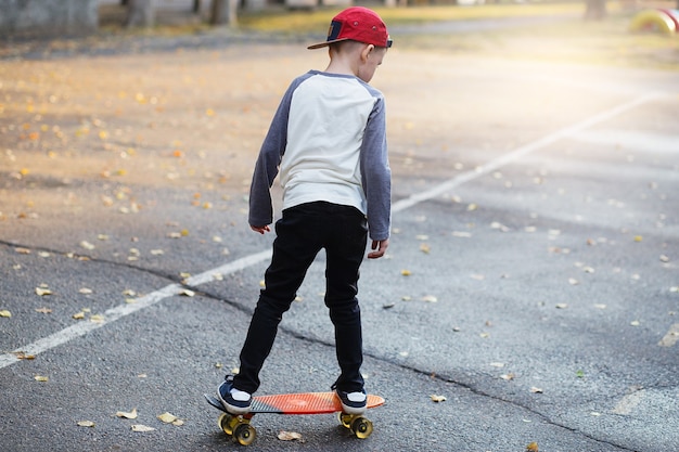 Ragazzino urbano con uno skateboard da penny. Ragazzino che guida nel parco su uno skateboard