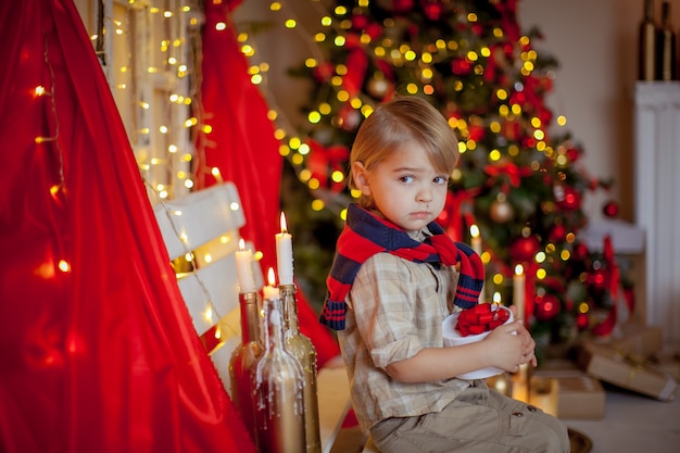 Ragazzo 4-6 anni in una sala festiva rossa e una bella acconciatura alla vigilia di Capodanno