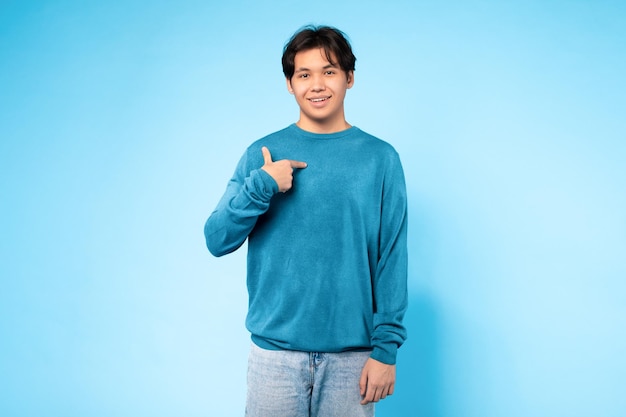 Ragazzo adolescente asiatico che punta a se stesso con fiducia sfondo blu