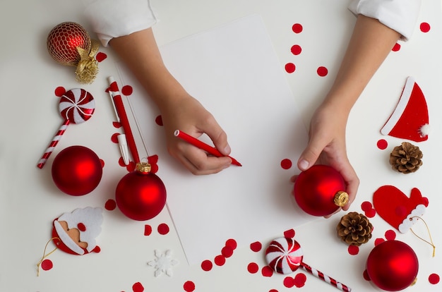 Ragazzo adolescente biondo vestito con una camicia bianca che scrive una lettera a Babbo Natale a casa