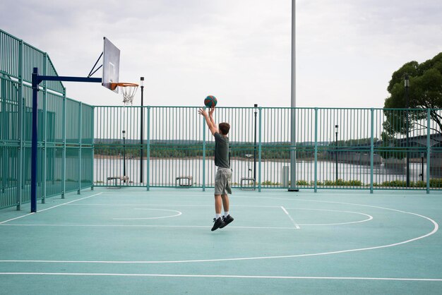 Ragazzo adolescente che gioca a basket nel parco giochi della città vita attiva hobby sport per bambini