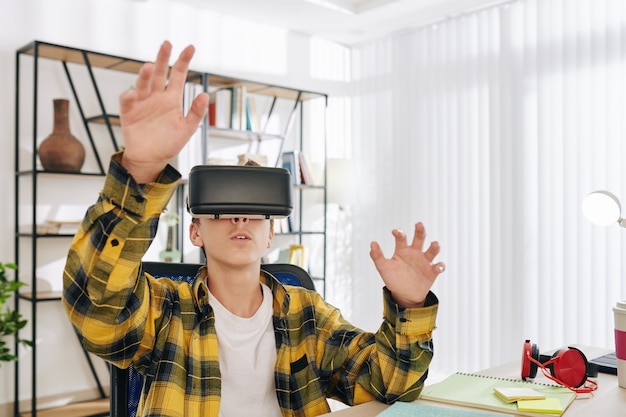 Ragazzo adolescente entusiasta di testare un nuovo gioco o un'applicazione educativa con gli occhiali per realtà virtuale