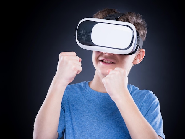 Ragazzo adolescente felice che indossa occhiali di realtà virtuale guardando film o giocando a videogiochi Adolescente sorridente allegro che guarda con gli occhiali VR Bambino divertente che sperimenta la tecnologia 3D da vicino