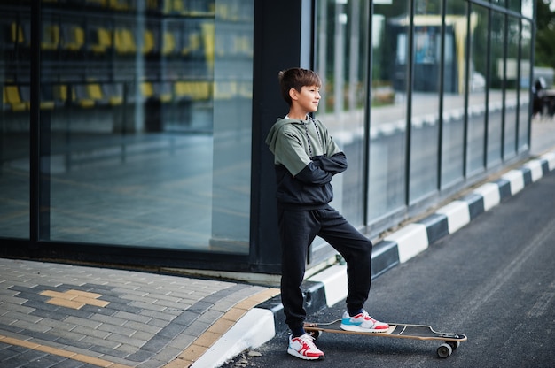 Ragazzo adolescente in una tuta sportiva con longboard.