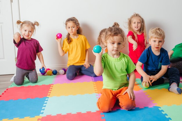 Ragazzo adorabile del bambino che gioca con le palline e il cestino di plastica