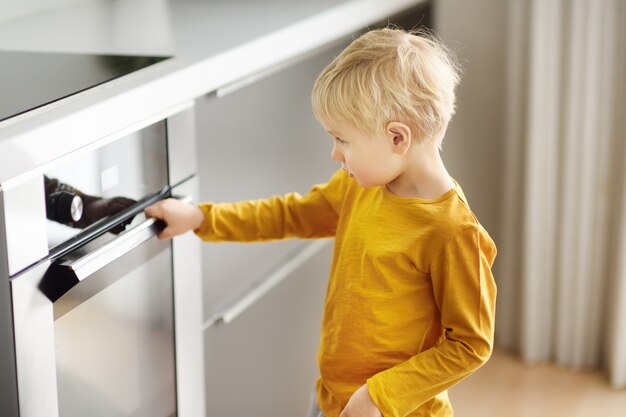 Ragazzo affascinante che aspetta preparando alimento in cucina domestica.