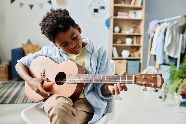 Ragazzo africano che impara a suonare la chitarra