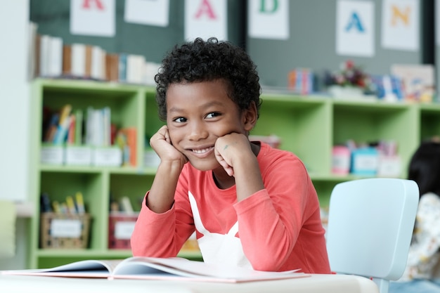 Ragazzo africano seduto alla sua scrivania con la faccia sorridente