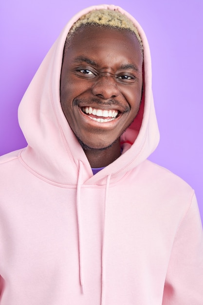 Ragazzo afro sorridente ottimista in pullover rosa alla moda