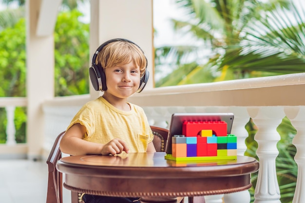 Ragazzo ai tropici che parla con amici e familiari in videochiamata utilizzando un tablet e cuffie wireless