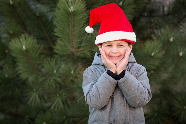 Ragazzo all'aperto che indossa il cappello di Babbo Natale felice