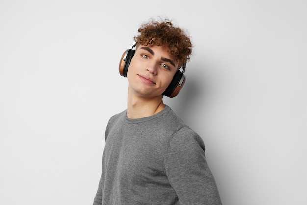 Ragazzo alla moda che ascolta la musica in cuffie emozioni sfondo chiaro