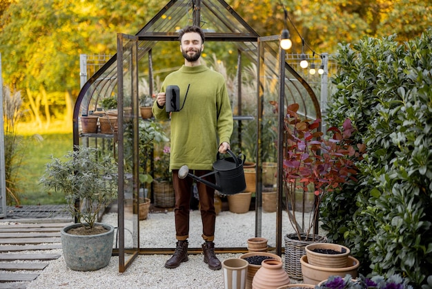 Ragazzo alla moda con annaffiatoio in giardino