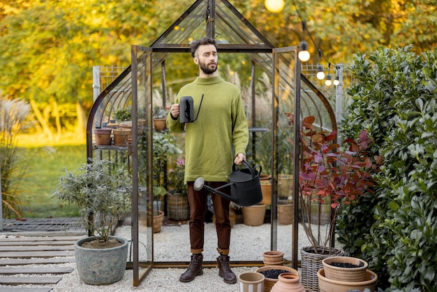 Ragazzo alla moda con annaffiatoio in giardino