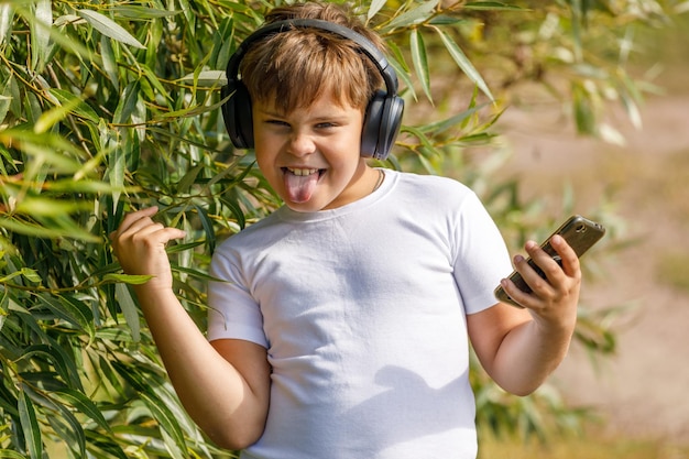 Ragazzo alla moda in cuffia con smartphone che ascolta musica nel parco