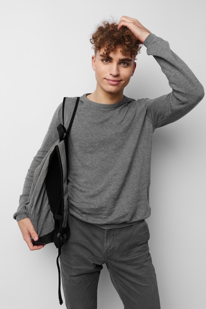 Ragazzo alla moda in un maglione grigio zaino moda sfondo isolato