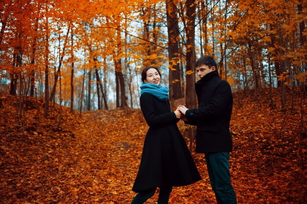 Ragazzo allegro e ragazza nel parco in autunno, tenendosi per mano