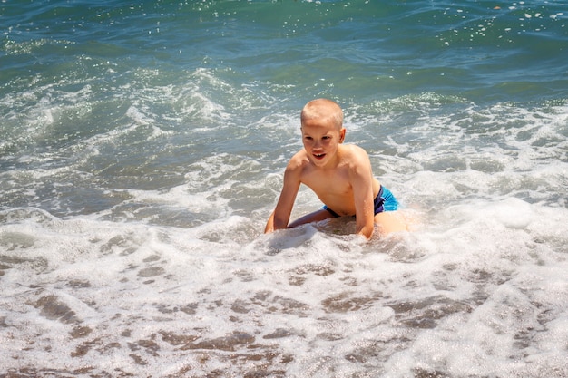 ragazzo allegro si bagna nelle onde del mare