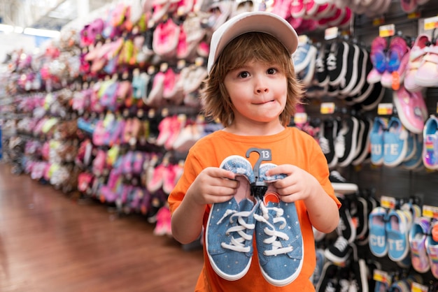 Ragazzo americano sorridente con scarpe bambini nel negozio di scarpe