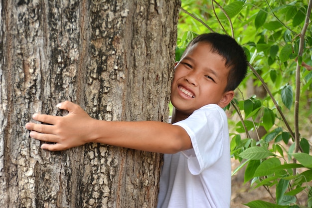 Ragazzo asiatico che abbraccia un albero