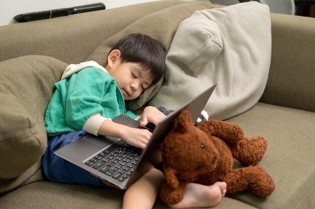 Ragazzo asiatico che dorme mentre studia online sul computer portatile