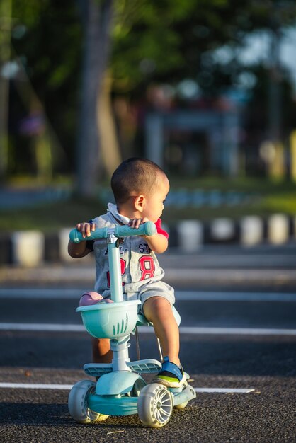 Ragazzo asiatico che gioca allo scooter. Bambino carino.