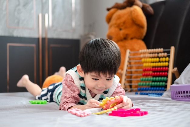 Ragazzo asiatico che gioca con gioia con i puzzle sul letto