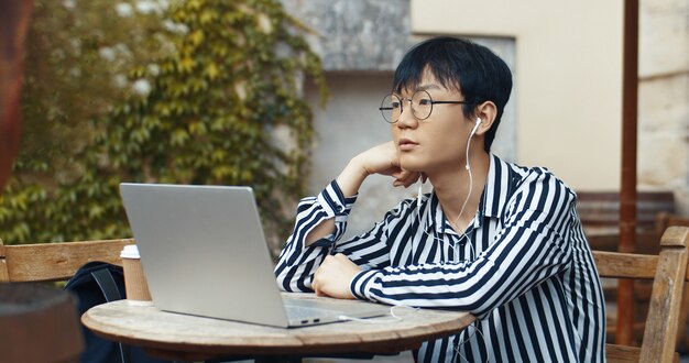 Ragazzo asiatico che lavora al computer portatile sulla terrazza