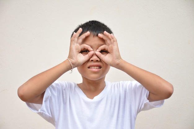 Ragazzo asiatico che usa la mano un cerchio intorno all'occhio