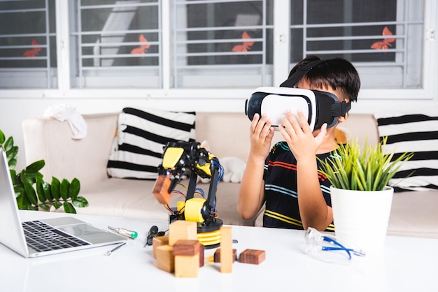 Ragazzo asiatico che usa occhiali VR sul braccio robotico in officina