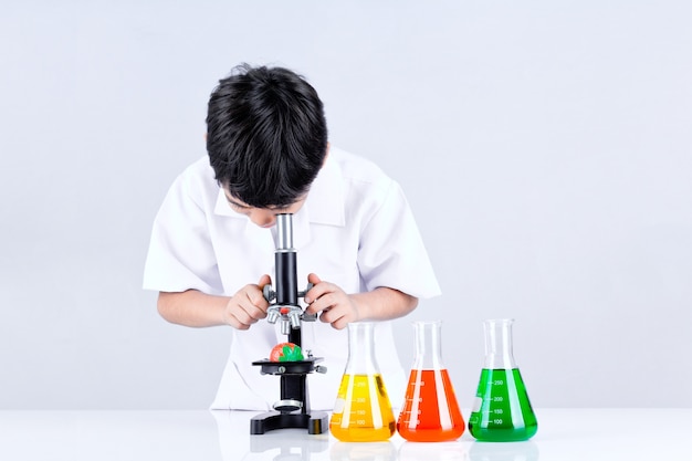Ragazzo asiatico condurre un microscopio esperimento