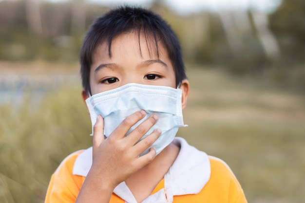 Ragazzo asiatico del bambino che indossa una maschera di protezione per prevenire il virus Corona