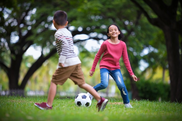 ragazzo asiatico e ragazza godendo con partita di calcio all&#39;aperto