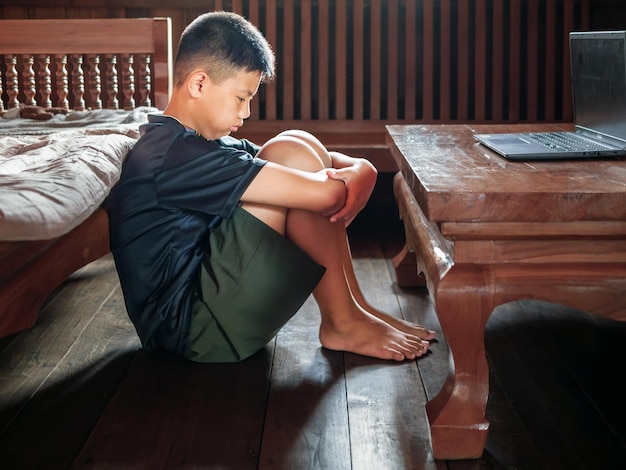 Ragazzo asiatico sconvolto seduto al buio pensando a conflitti relazioni familiari faccia triste