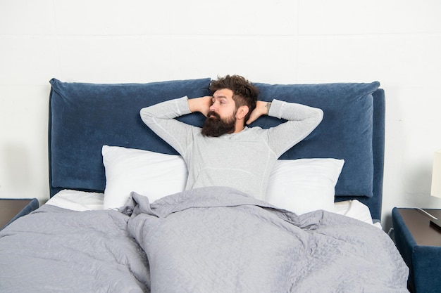 Ragazzo assonnato che è a letto sveglio dopo aver dormito la mattina