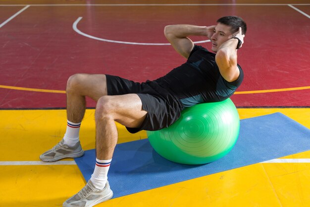 Ragazzo atletico in abbigliamento sportivo e fitness tracker facendo esercizi in palestra.