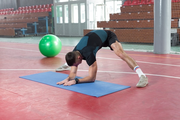 Ragazzo atletico in abbigliamento sportivo e fitness tracker facendo esercizi in palestra.