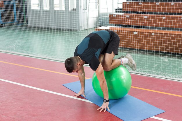 Ragazzo atletico in abbigliamento sportivo e fitness tracker facendo esercizi in palestra.